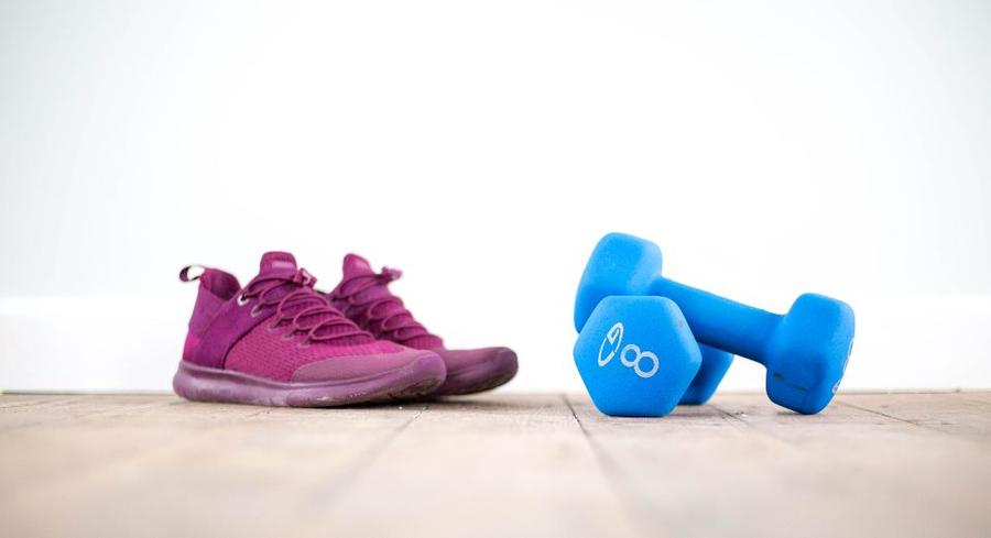 Zapatillas y mancuernas livianas en el piso de una casa, imagen ilustrativa