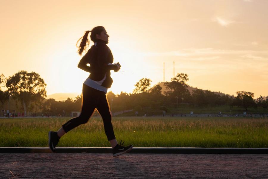 Silueta de una mujer corriendo por un sendero al atardecer