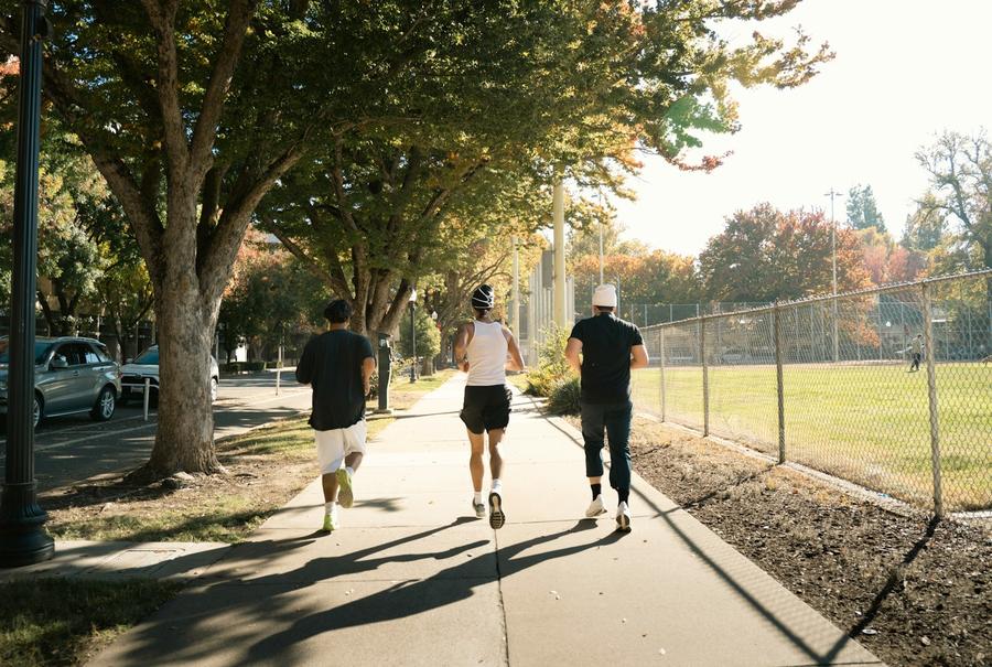 Tres personas trotando en una vereda soleada
