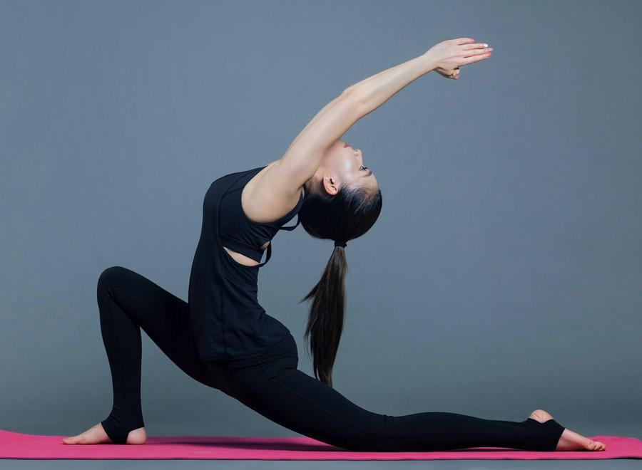 Mujer con top negro y calzas negras haciendo yoga