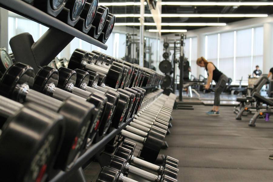 Mujer parada rodeada de equipos de gimnasio