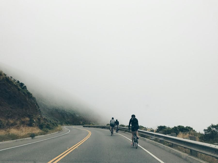 Tres hombres andando en bicicleta por un camino asfaltado
