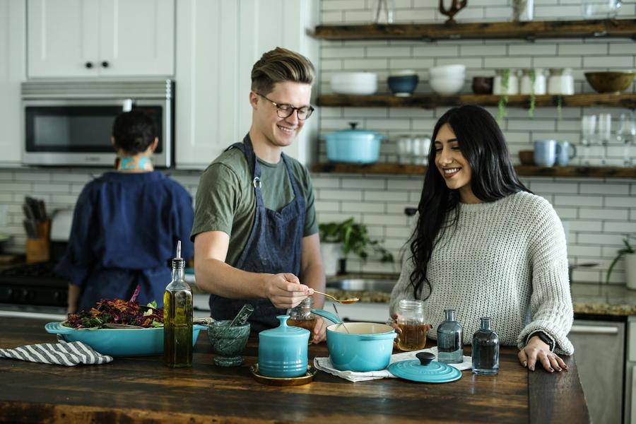 Hombre sonriente mezclando cerca de una mujer en la cocina