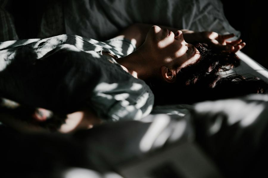 Persona acostada en la cama con la cabeza en una almohada