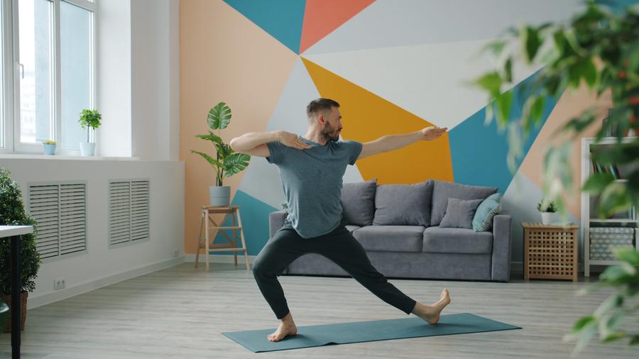 Hombre haciendo yoga sobre un mat en una habitacion colorida