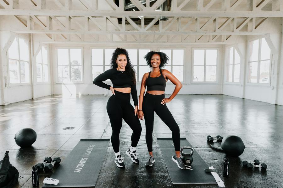 Dos mujeres paradas sobre esterillas en un gimnasio