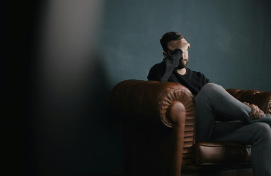 Hombre sosteniendose la cabeza sentado en un sofa