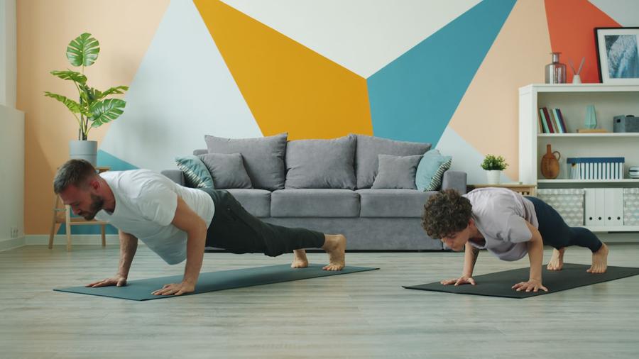 Pareja haciendo flexiones sobre esterillas de yoga en el living