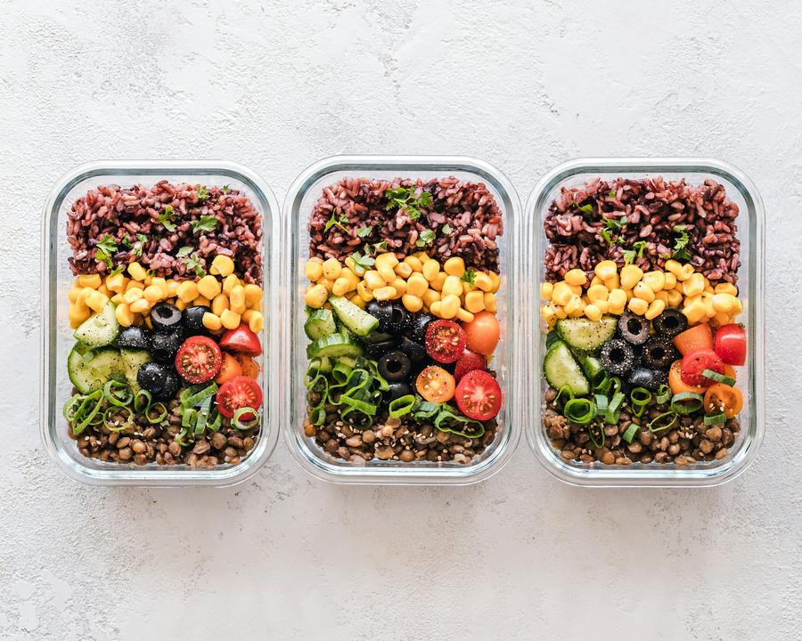 Tres recipientes de vidrio con arroz, choclo, aceitunas y verduras