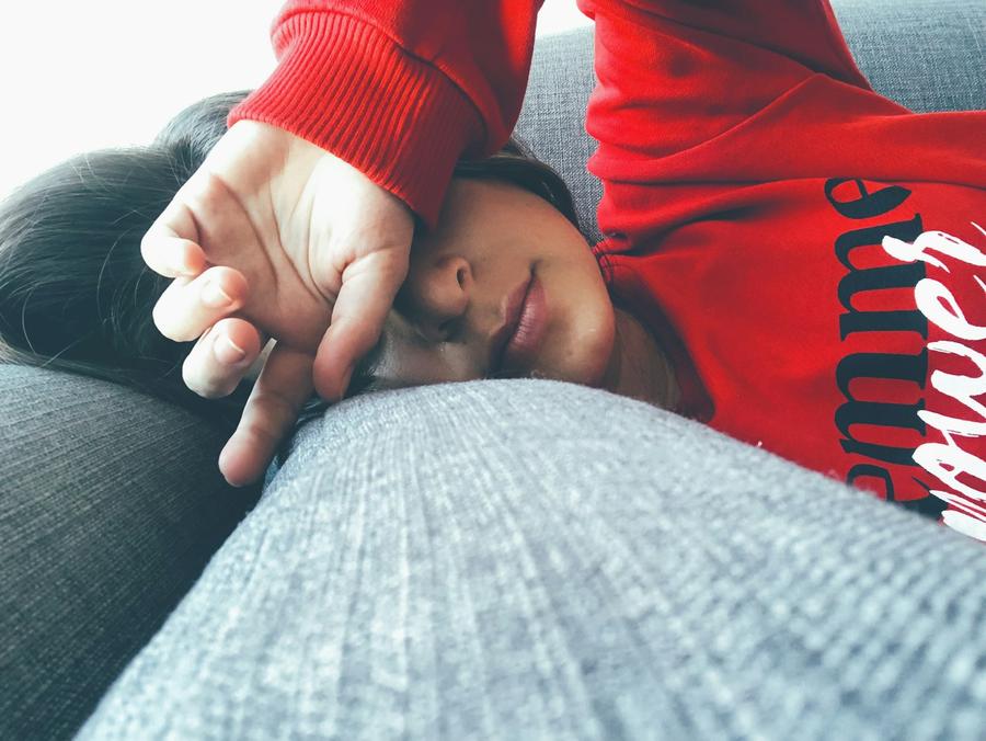 Mujer con suéter rojo recostada sobre una superficie gris