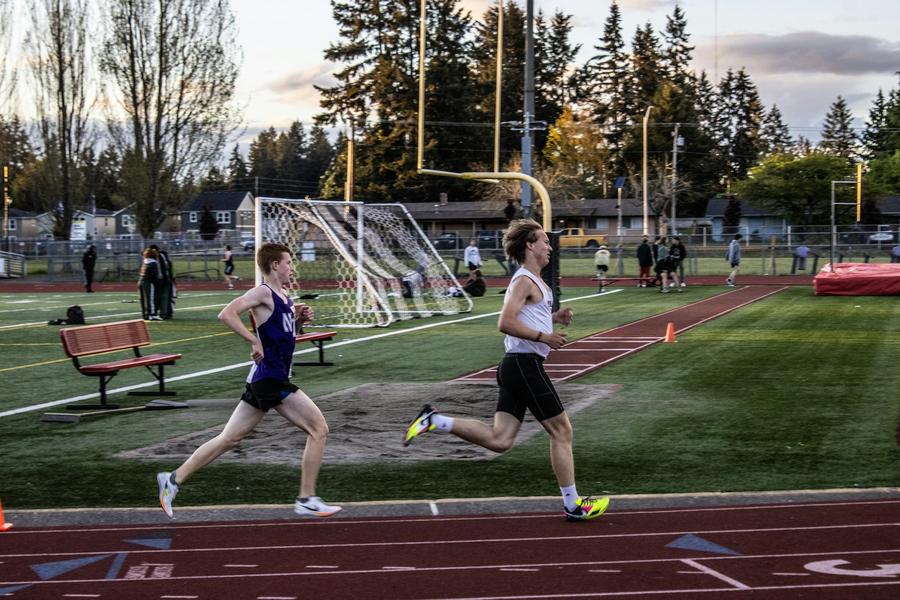 Dos personas corriendo juntas en una pista de atletismo al atardecer
