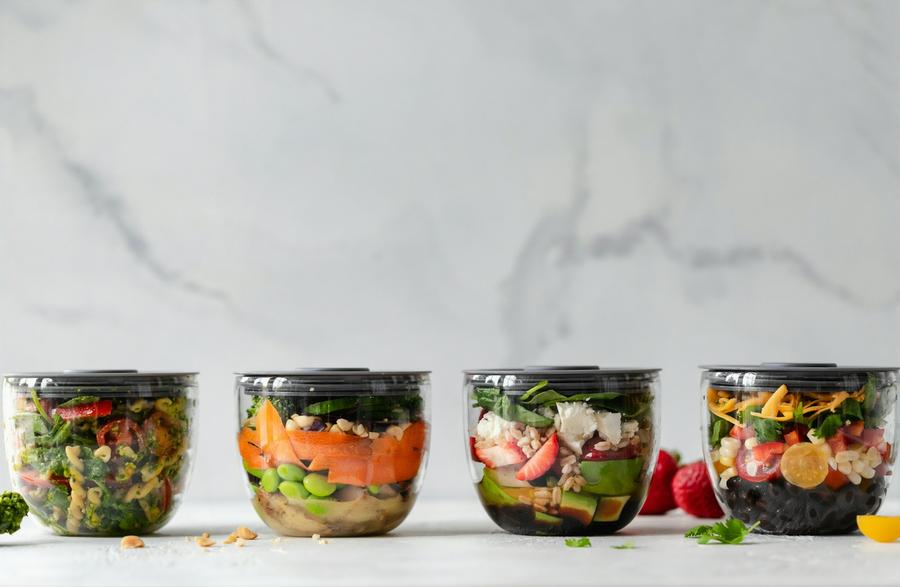 Cuatro bowls de plástico transparente con verduras