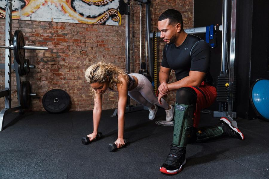 Hombre ayudando a otro hombre a hacer flexiones