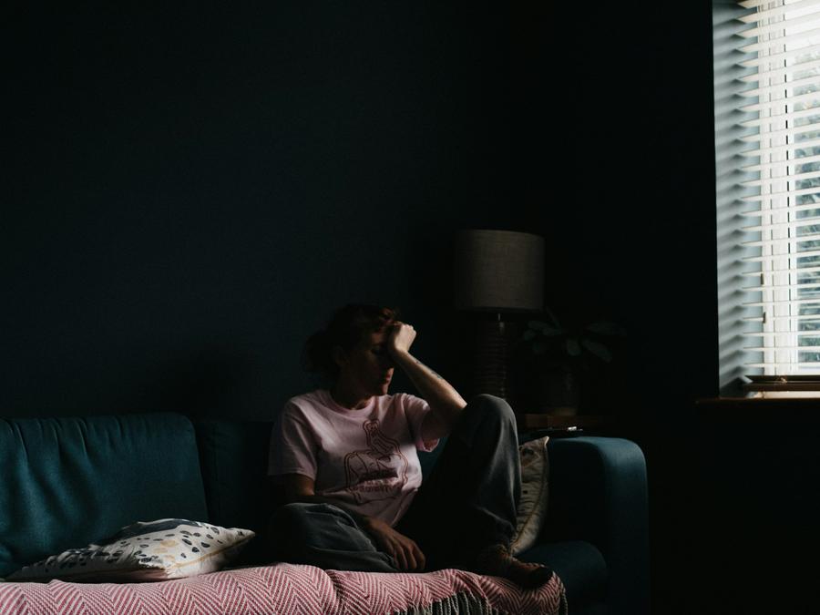 Mujer con vestido violeta sentada en un sofa