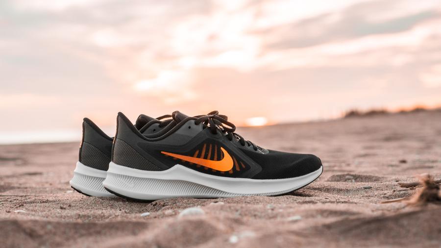 Zapatillas atléticas blancas y negras sobre arena marrón